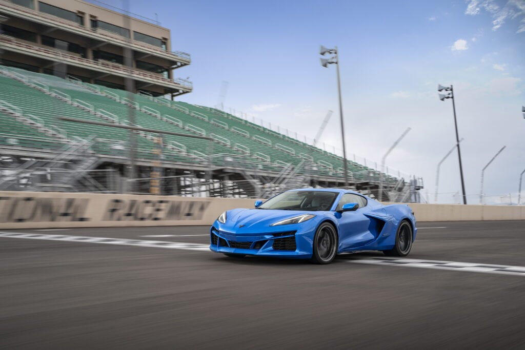 Front 3/4 view of a 2024 Corvette E-Ray 3LZ coupe in Riptide Blue Metallic crossing the finish line on a track. Pre-production model shown. Actual production model may vary. Model year 2024 Corvette E-Ray available 2023.
