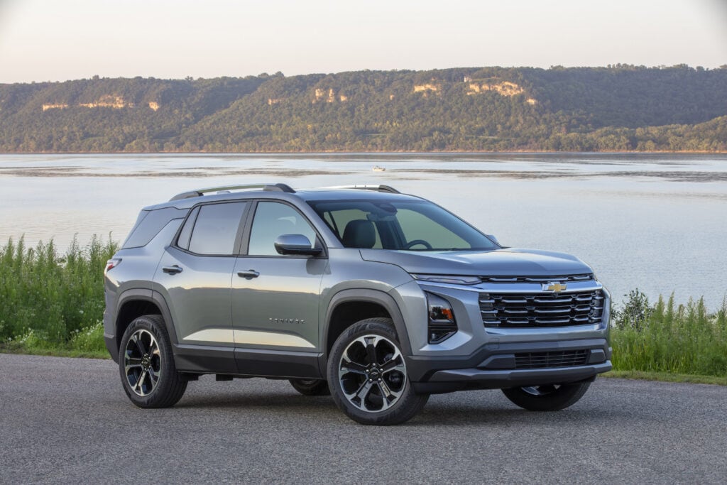 Front 3/4 view of a 2025 Chevrolet Equinox LT in Sterling Gray Metallic parked near a large body of water.