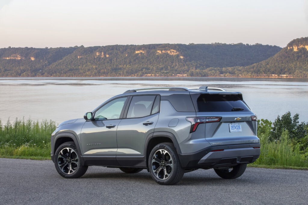 Rear 3/4 view of a 2025 Chevrolet Equinox LT in Sterling Gray Metallic parked near a large body of water.