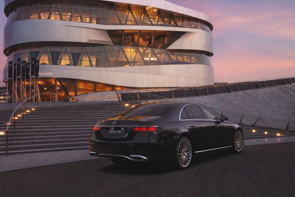 2027 Mercedes-Benz S-Class shown from the side and rear in front of a large building.