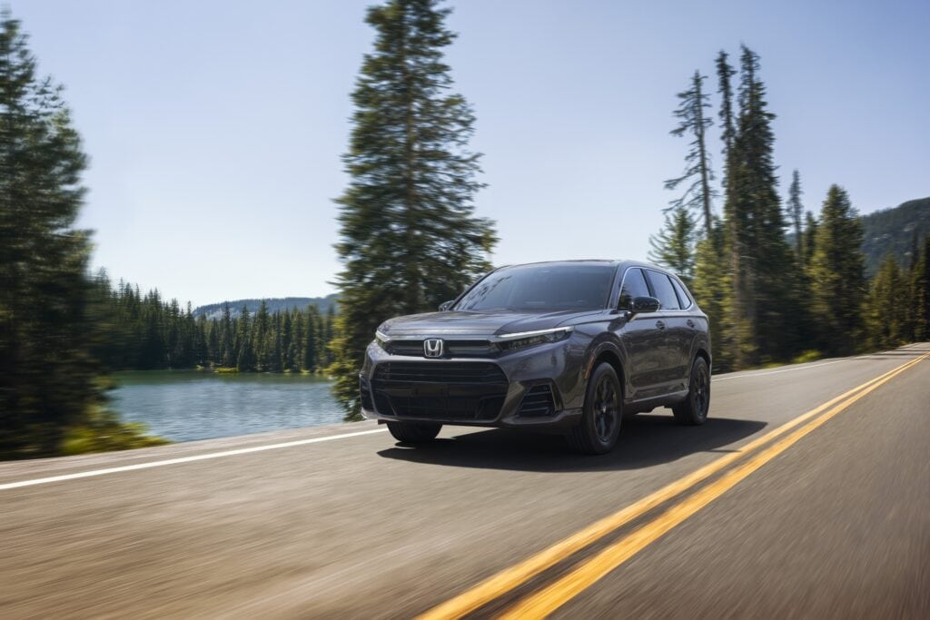 2025 Honda CR-V driving along a lake amongst pine trees.