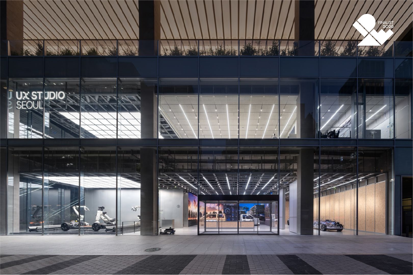 Glass-fronted UX Studio Seoul building with lit exhibits visible inside.