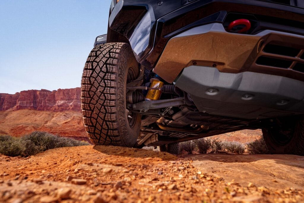 2027 Chevrolet Silverado 1500 ZR2 in White Sands. Tight detail shot on Multimatic DSSV Dampers under front passenger wheel.