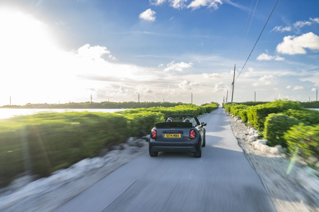 Rear end of the Mini convertible speeding through bushes on the road