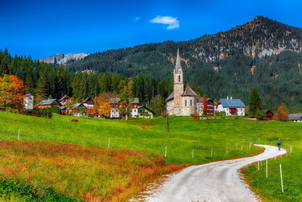 Alpine green fields and traditional wooden houses view of the Gosau village at autumn sunny day. Location: resort village Gosau Salzkammergut region, Gosau Valley in Upper Austria, Alps. Europe.