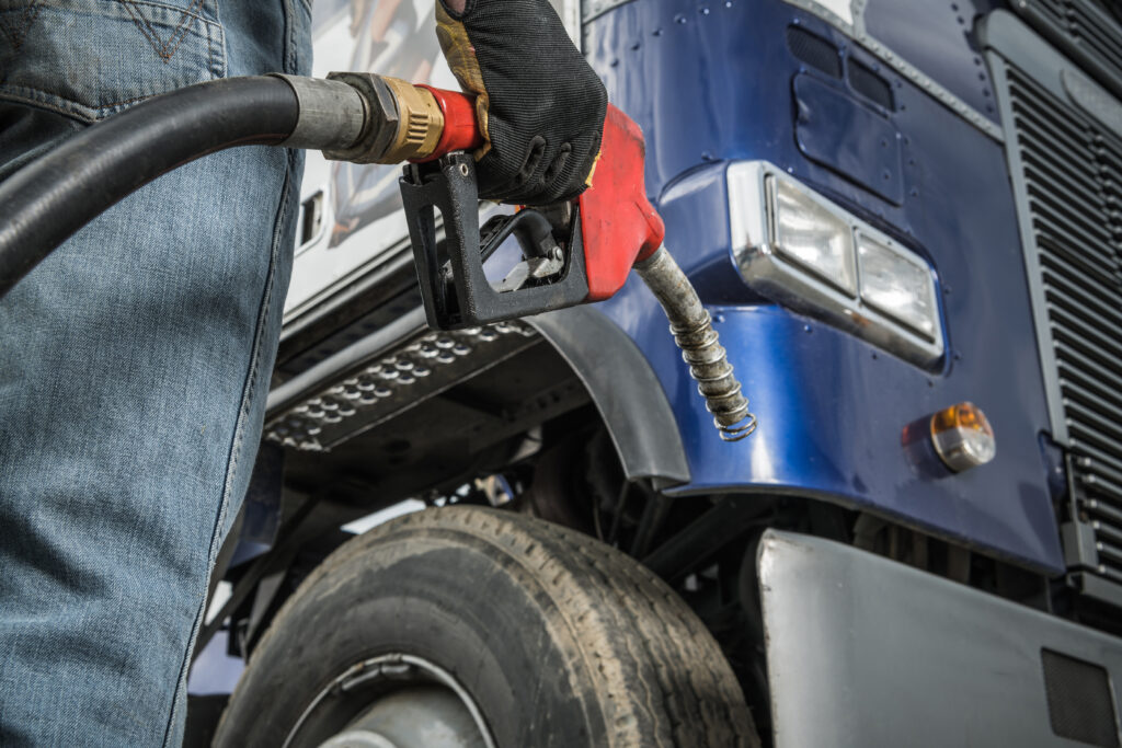 Trucker in Front of His Truck Preparing For Fueling Keeping Diesel Dispenser Pump Nozzle in His Hand. Transportation Industry.
