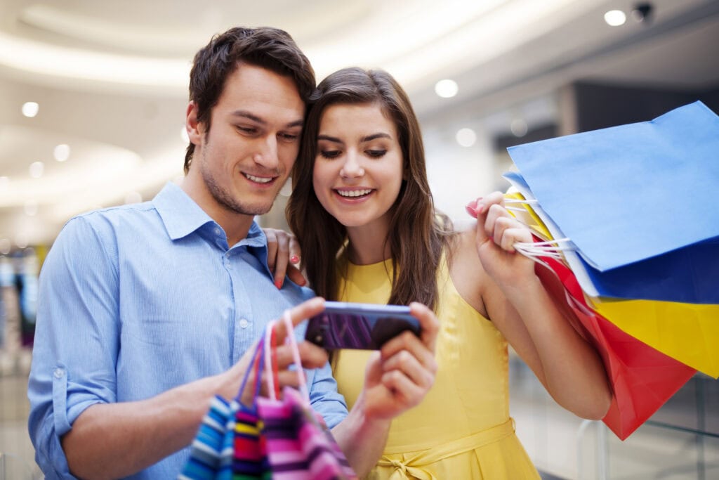 A smiling couple looking at a mobile phone, looking at Social Media to buy a car