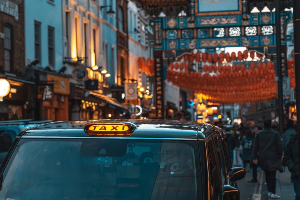 Black taxi cab parked on a london street adorned with chinese lanterns during chinese new year celebrations, creating a vibrant urban scene