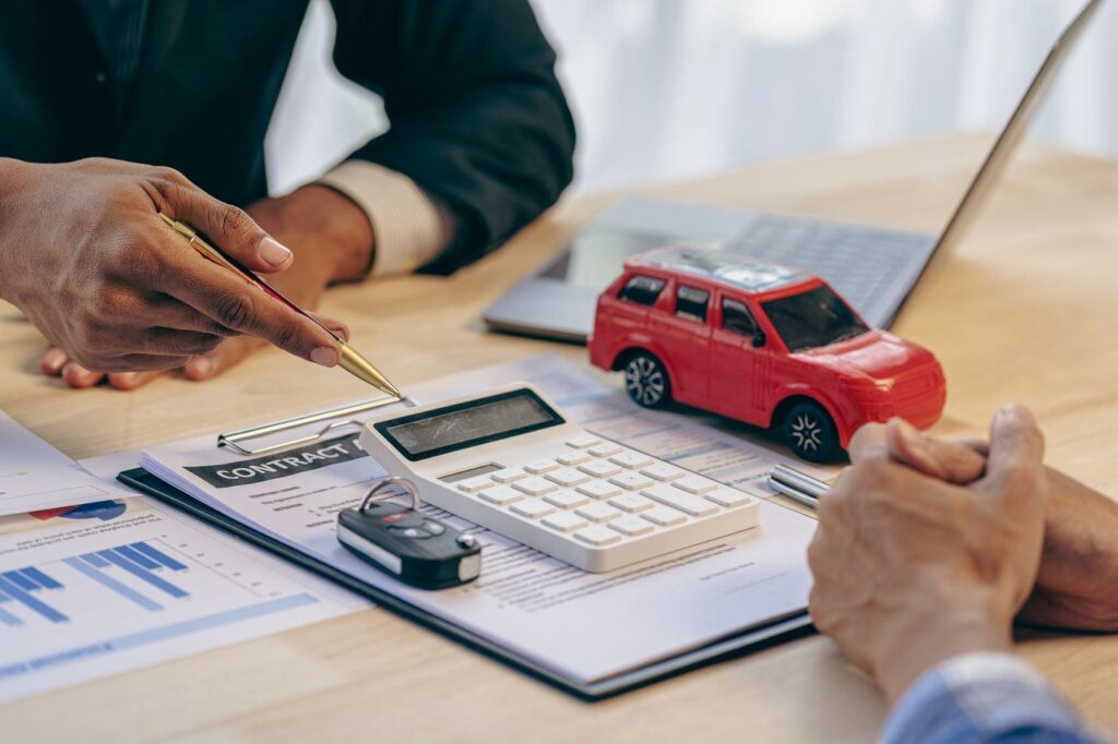 Hands of an auto loan generator walking somebody through their auto loan with a calculator