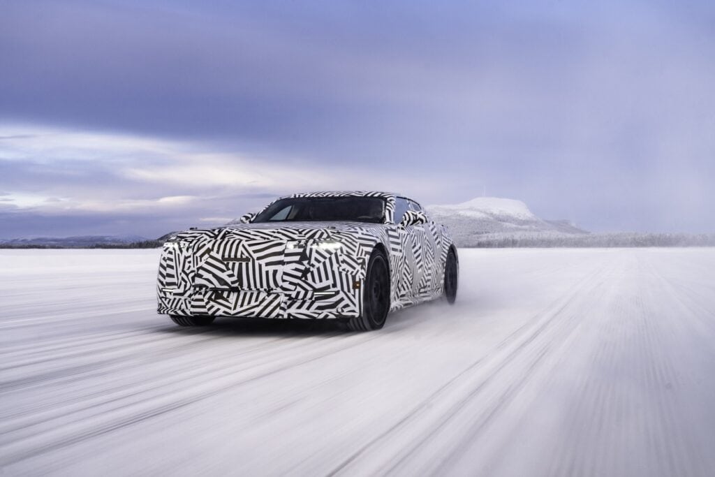 Camouflaged Jaguar Type 01 electric GT drives across snow during Arctic winter testing.