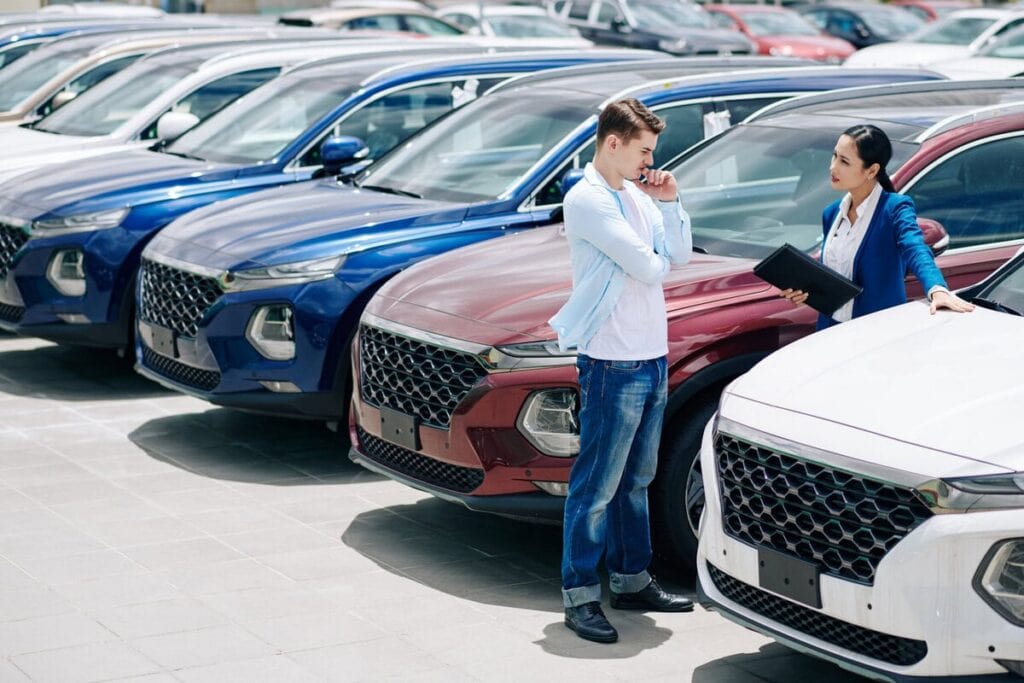 Pretty confident saleswoman showing car to pensive doubting young customer