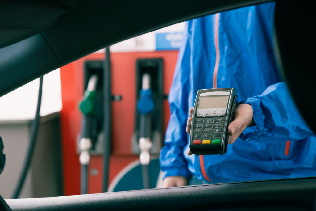 Closeup gas station staff worker with credit card swiping machine for fuel bill payment, Petroleum business