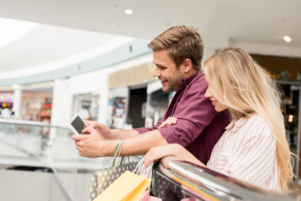 A smiling couple looking at a mobile phone, looking at Social Media to buy a car