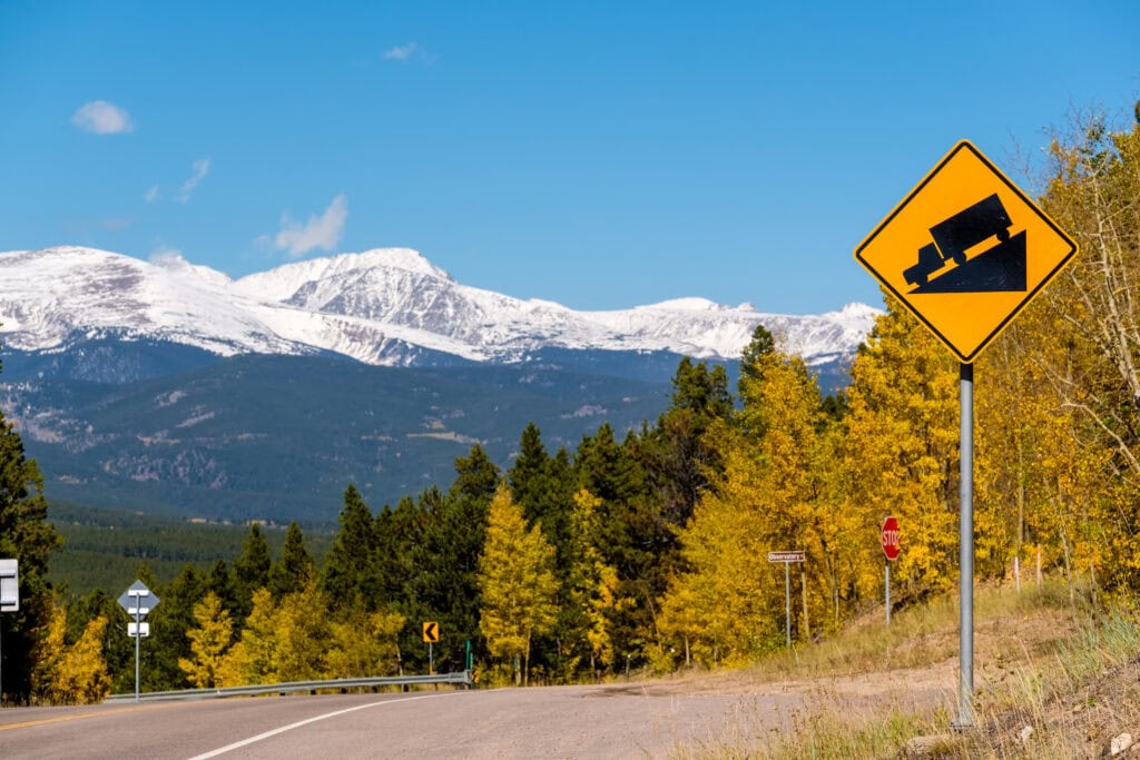 Steep grade truck road sign on highway at autumn sunny day in Colorado, USA.