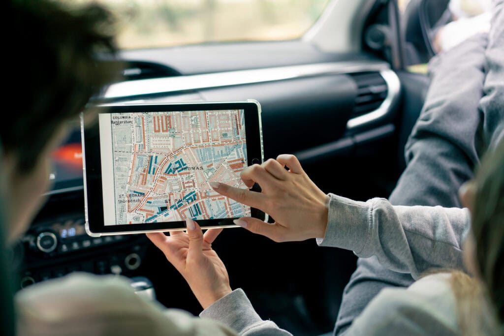 A couple in a car conferring and planning the best route through the forest using a map on a tablet
